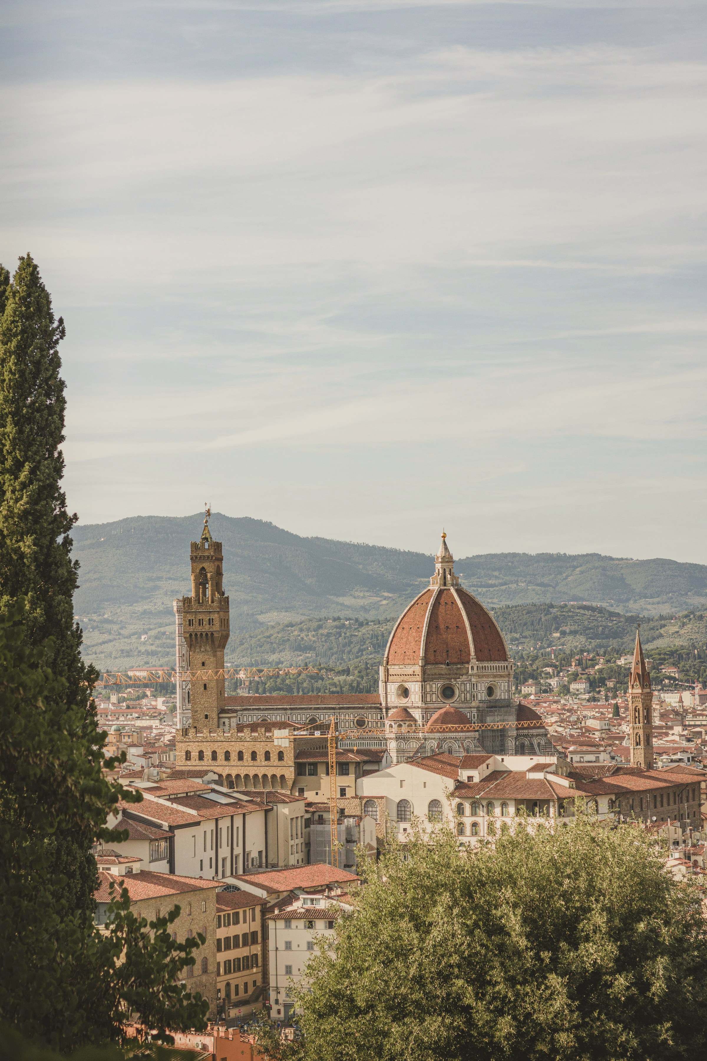 View over Florence to the cathedral dome and the Palazzo Vecchio tower, framed by a cypress