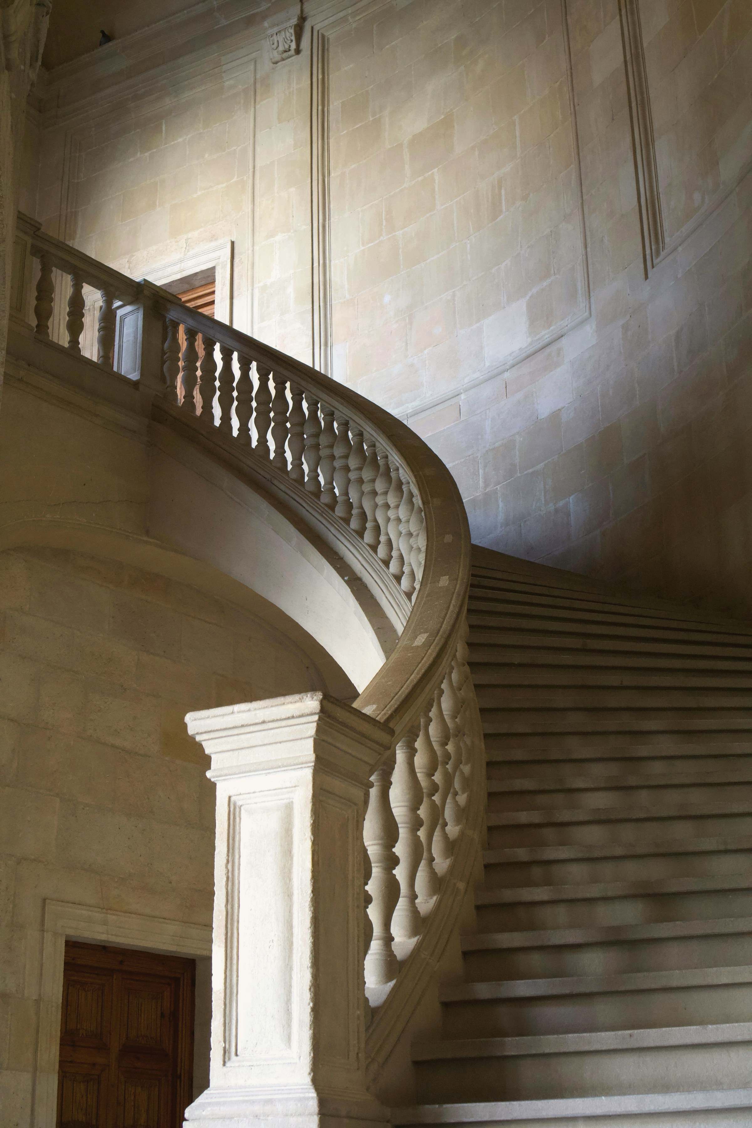 A curving stone staircase with a carved balustrade