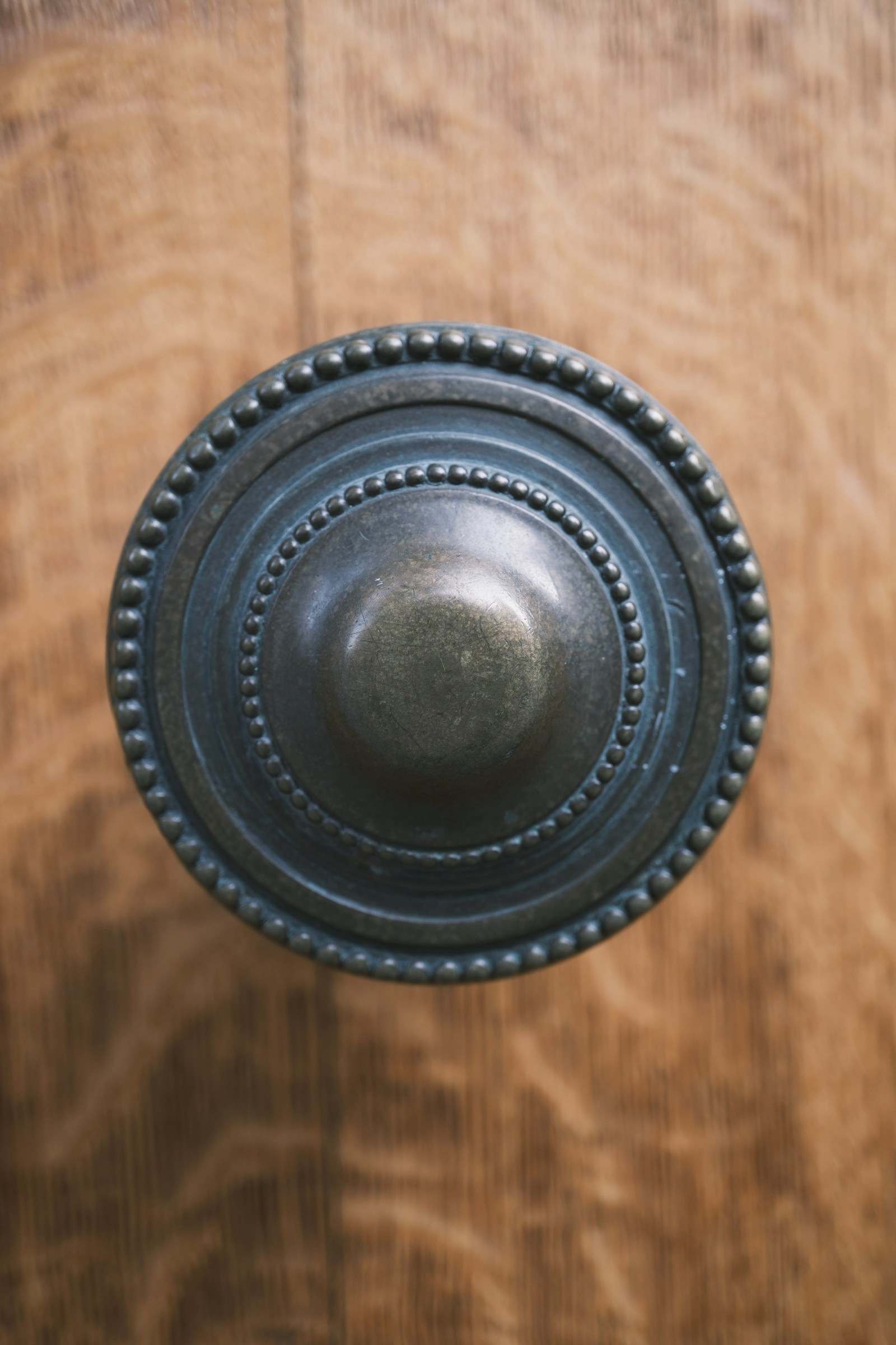 A patinated bronze door knob on warm wood